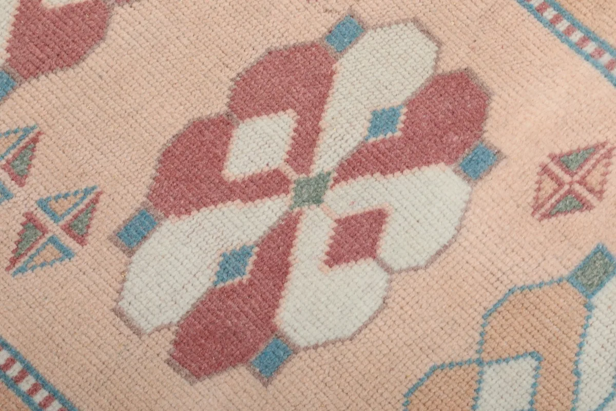Extreme close-up of a central rose and cream geometric motif with blue accents