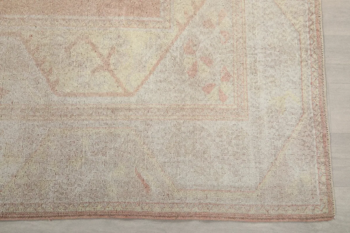 Detailed view of the corner of the rug, highlighting the geometric patterns and the subtle rose border.