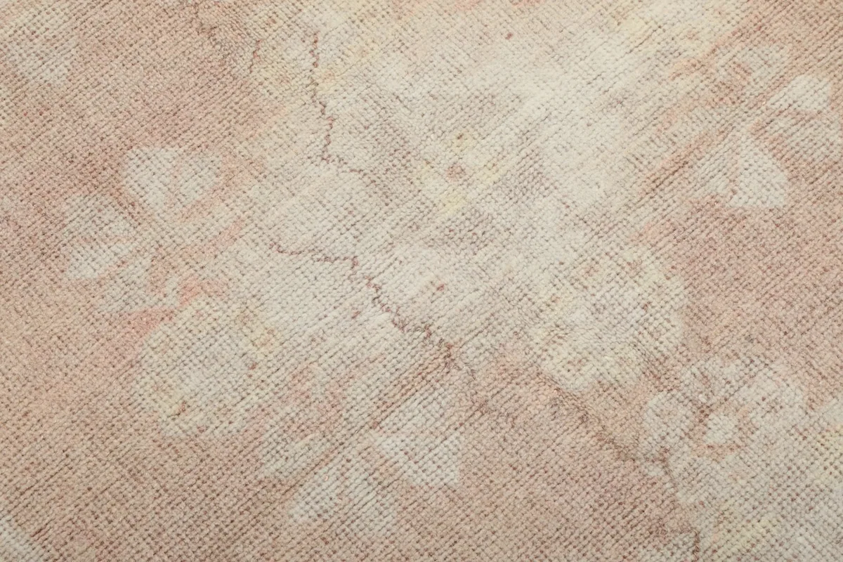 Close-up of the low wool pile texture and subtle variations in the rose and cream colors.