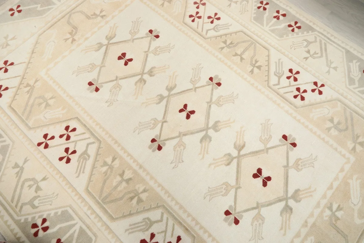 Close-up of the central ivory field with scattered red and beige geometric designs.