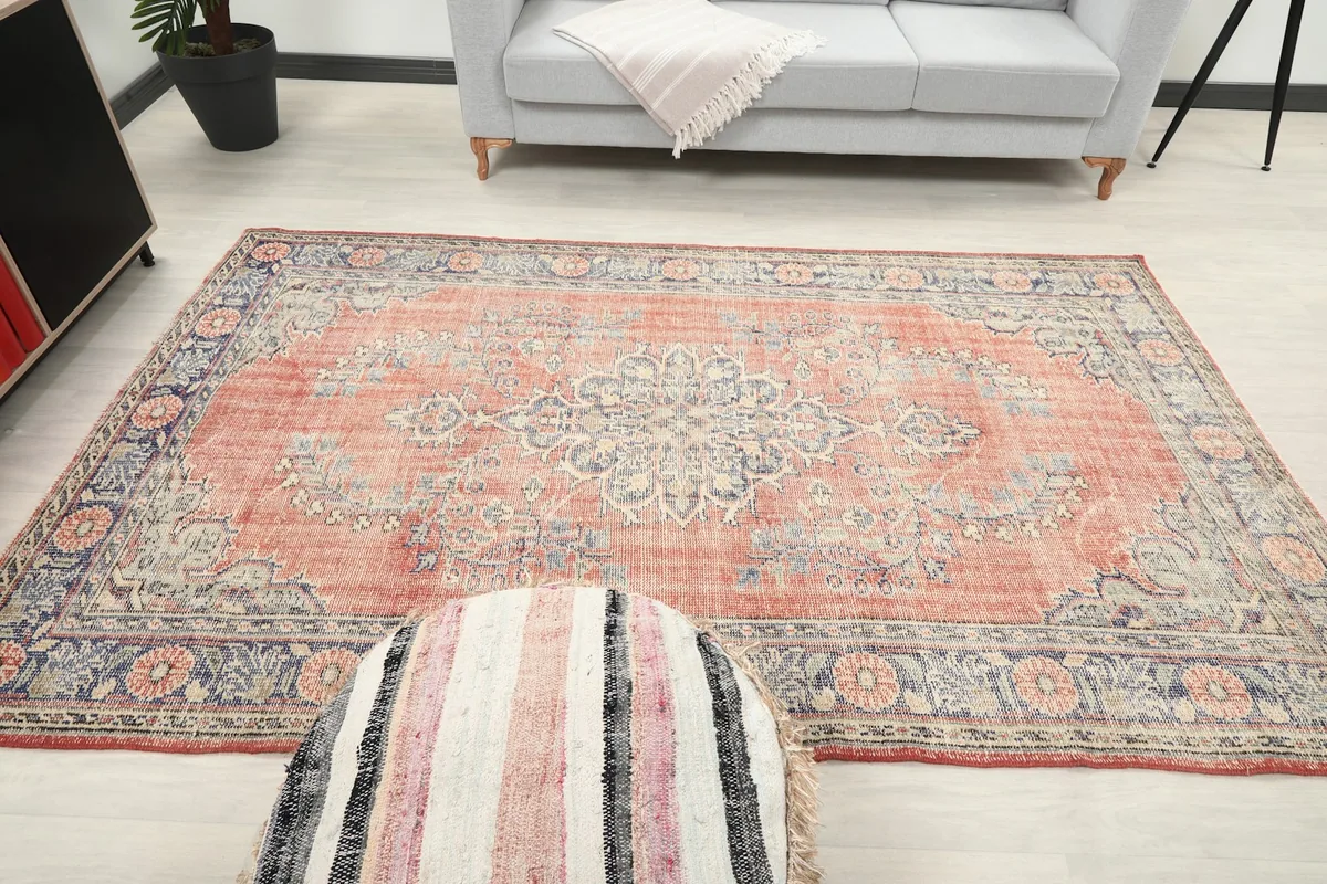 Overhead room shot of the rug with a striped pouf in the foreground