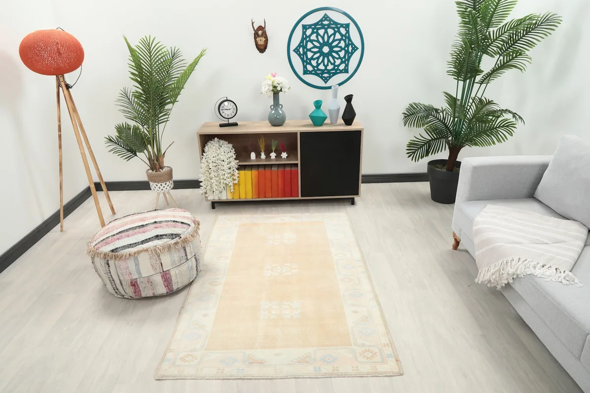 Vintage tan rug styled in a modern living space with light-colored furniture and plants