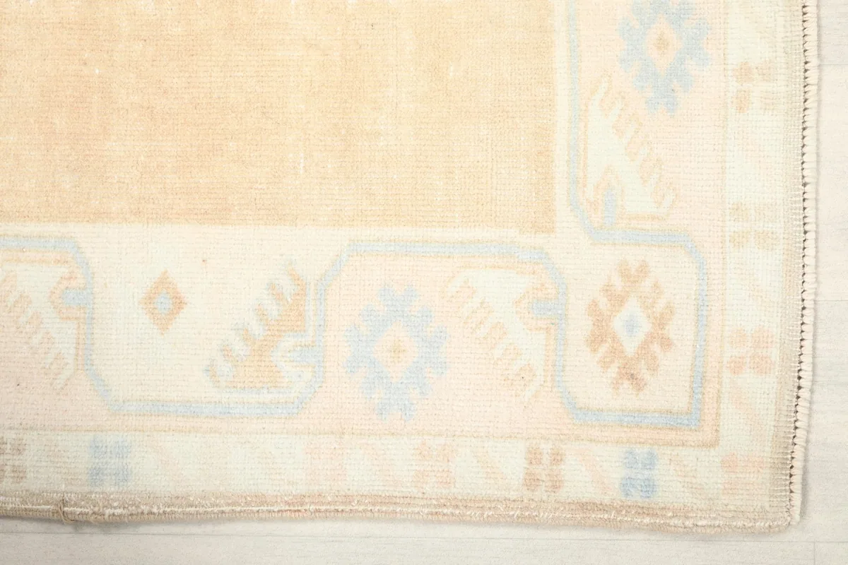 Detail of the rug's corner, showing the ivory border with blue and orange geometric motifs