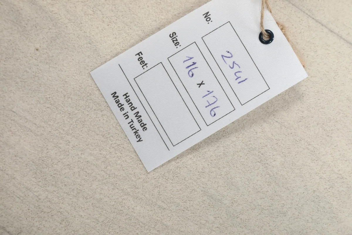 Product tag displaying the rug's size in centimeters (116 x 176) and 'Hand Made in Turkey'