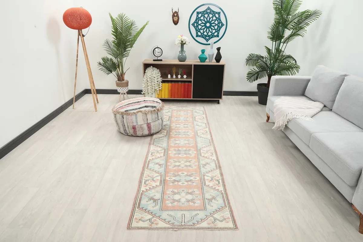 Peach and blue vintage runner rug in a modern living room setting with plants and a gray couch