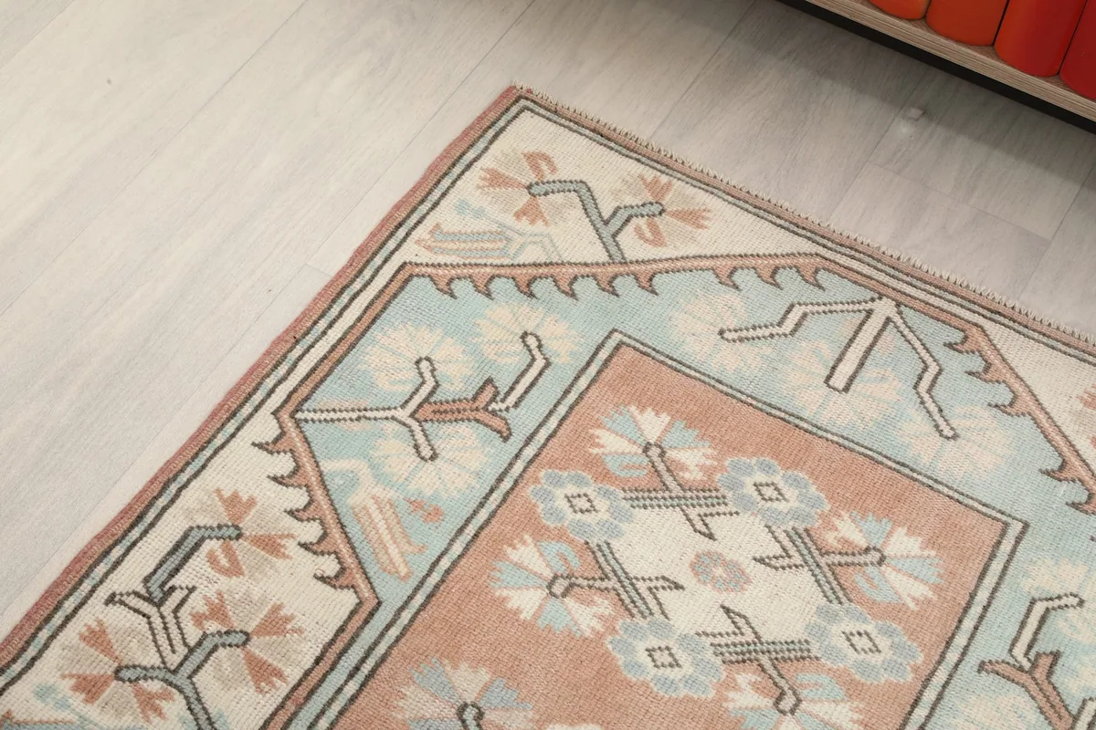 Close-up of a rug corner, highlighting the stylized floral and geometric elements in blue and ivory