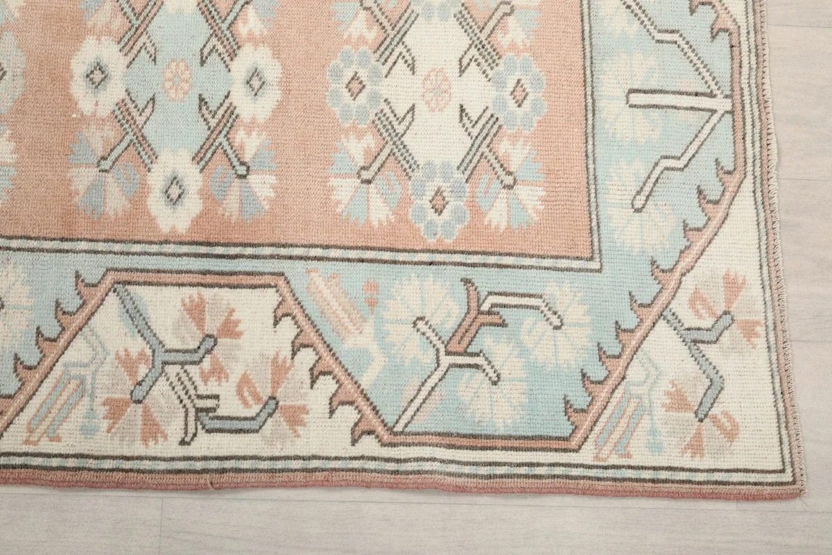 Corner detail of the runner rug, showing the blue border with geometric motifs and the peach field