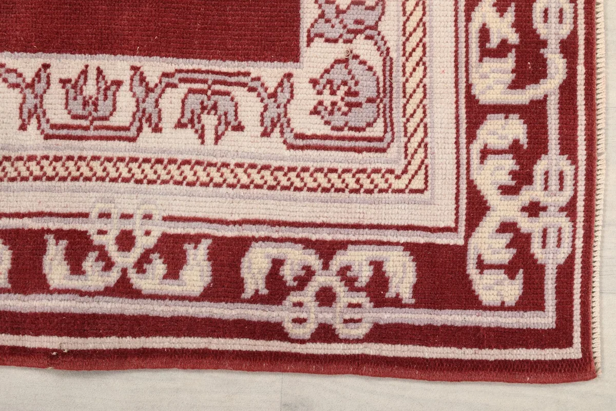 Detailed close-up of the corner of the rug, showing the cream geometric border patterns.