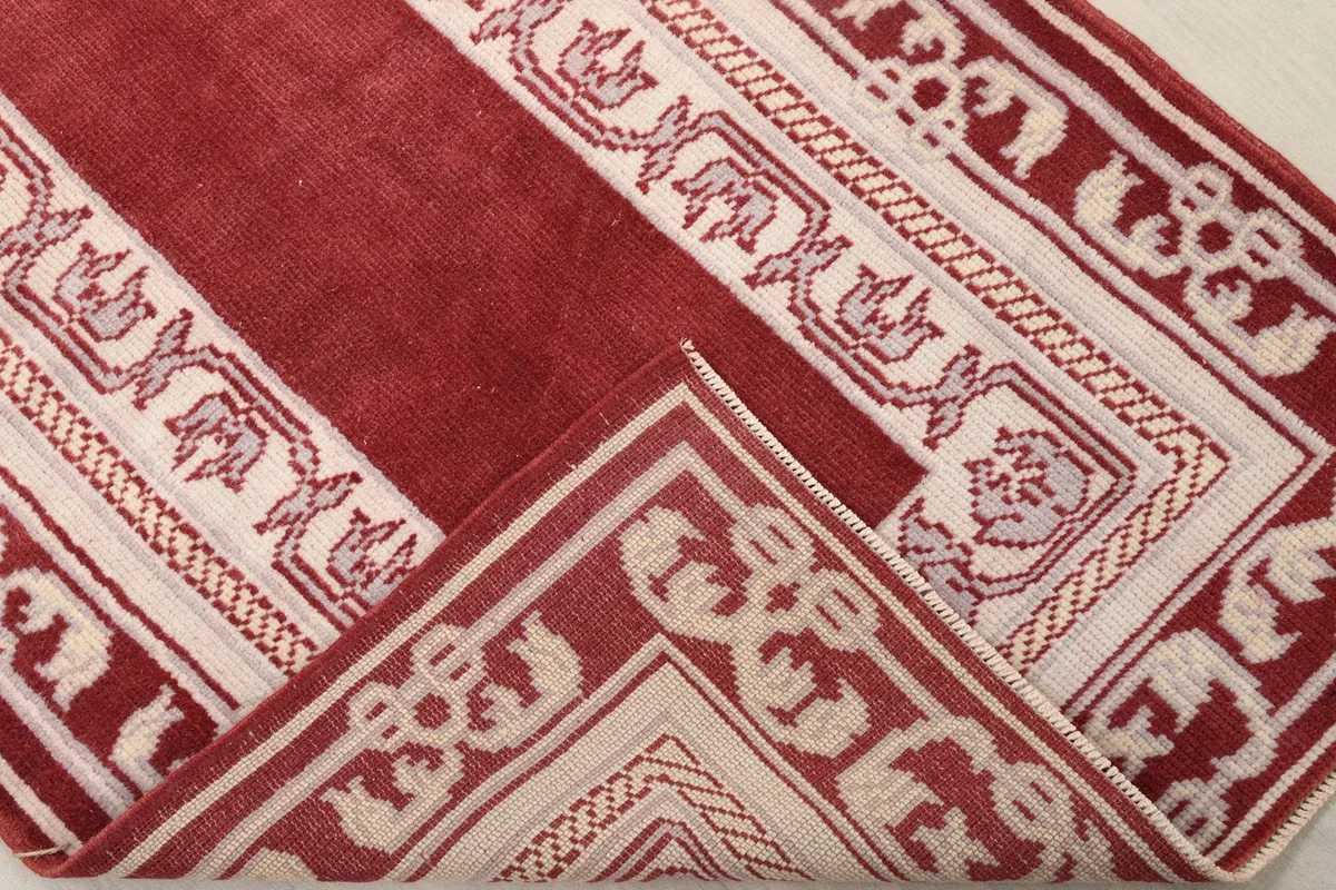 Folded corner of the rug, revealing the wool pile and cotton foundation construction.