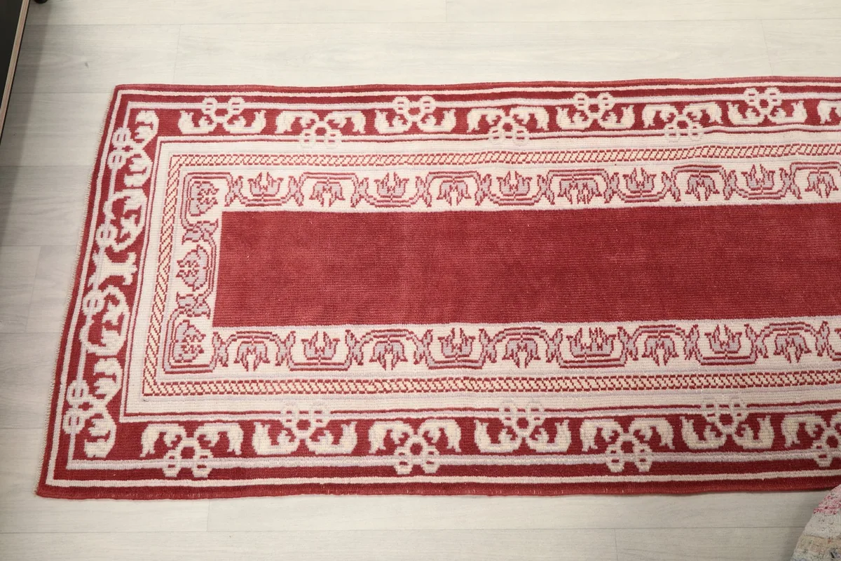 Overhead view of the rug's top half, showcasing the repeating border pattern and red center.