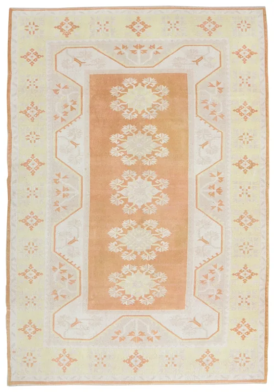 Full overhead view of the vintage orange and yellow floral Anatolian rug on a white background.