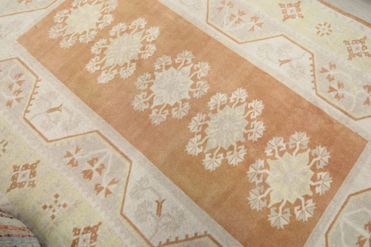 Diagonal view across the rug, highlighting the orange field with floral designs and the surrounding yellow border.