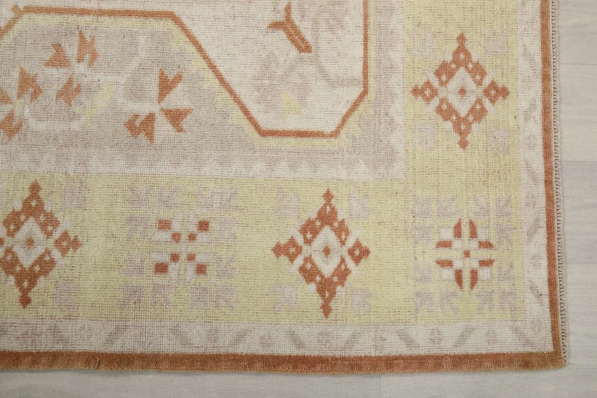 Detailed view of the yellow border with rust geometric patterns and the rug's edge.