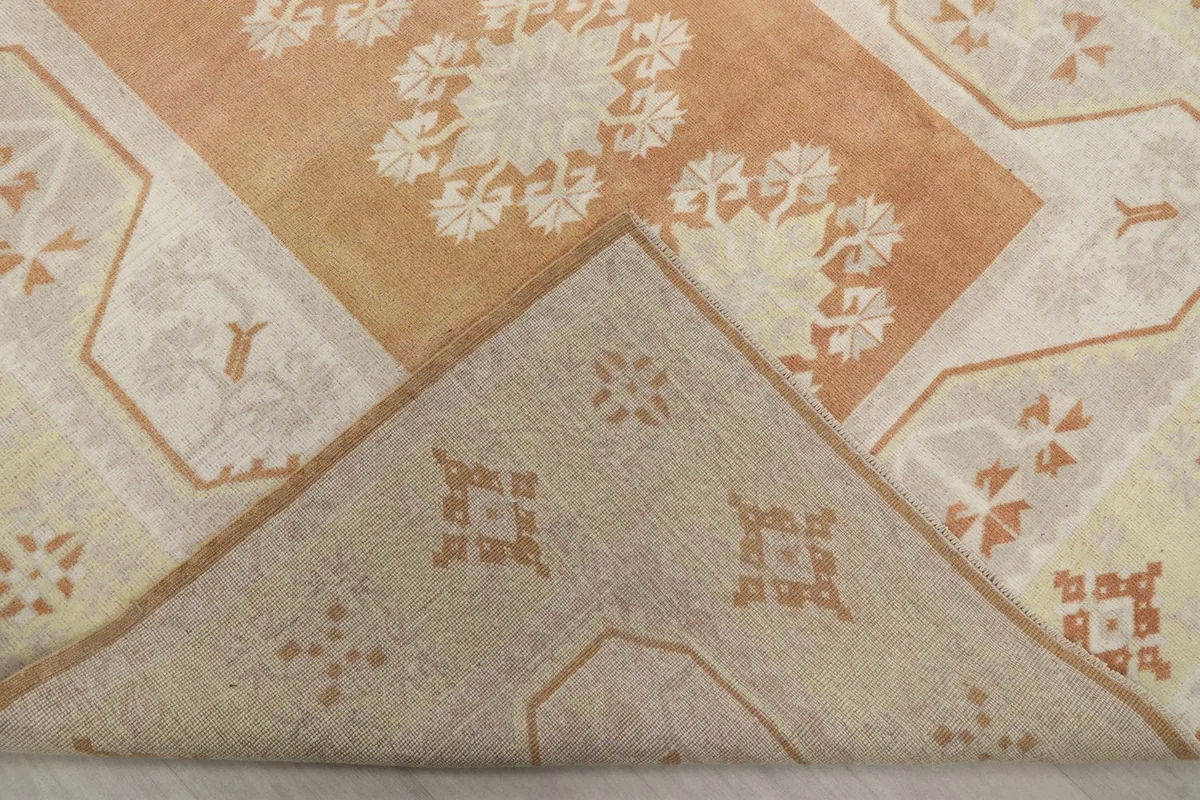 Corner of the rug folded back, revealing the cotton foundation and the reverse side of the hand-knotted construction.