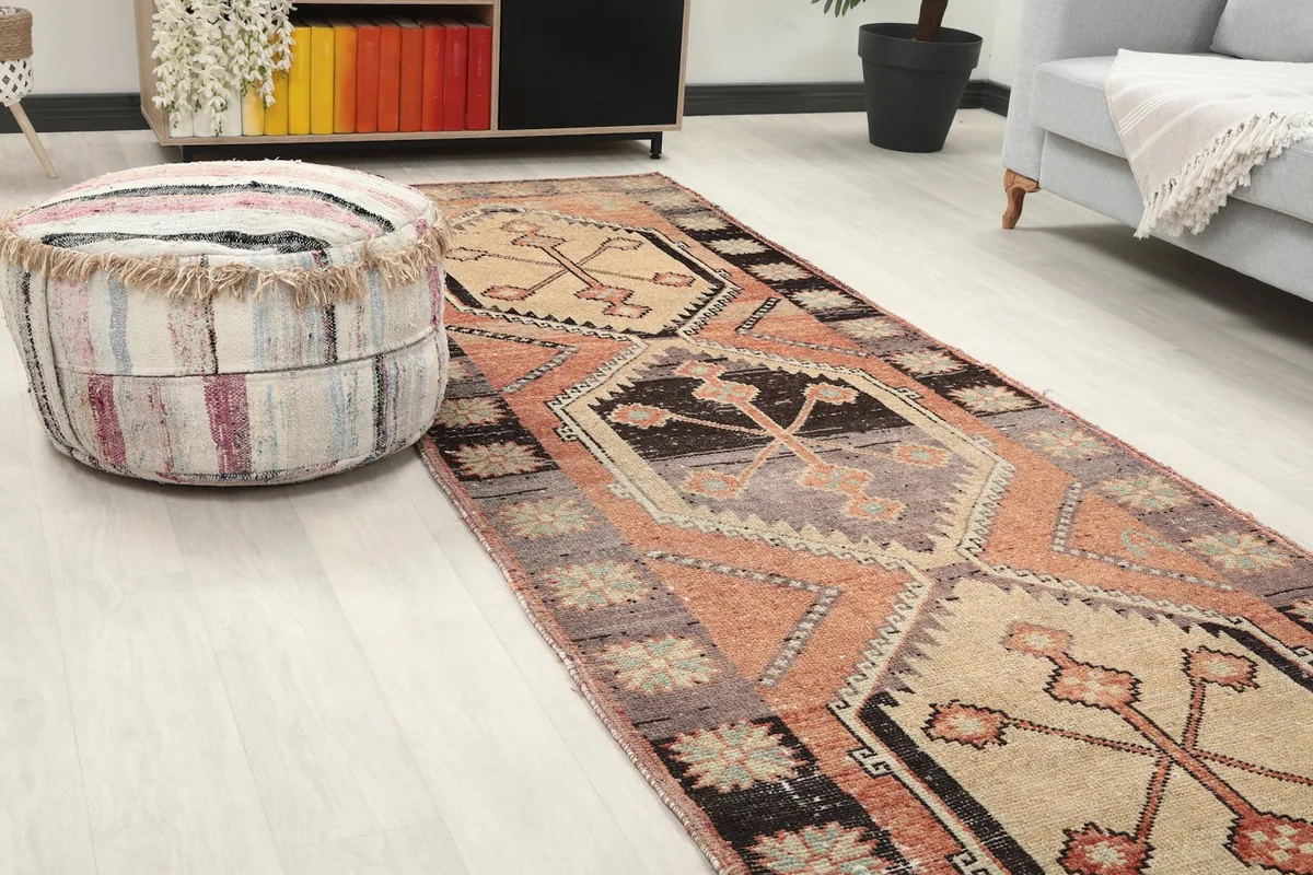 Close-up angled view of the runner rug's texture and colors next to a striped ottoman