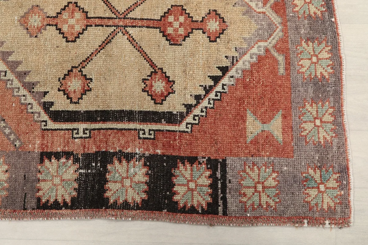 Detailed view of the rug's rust field, beige medallion, and gray floral border motifs