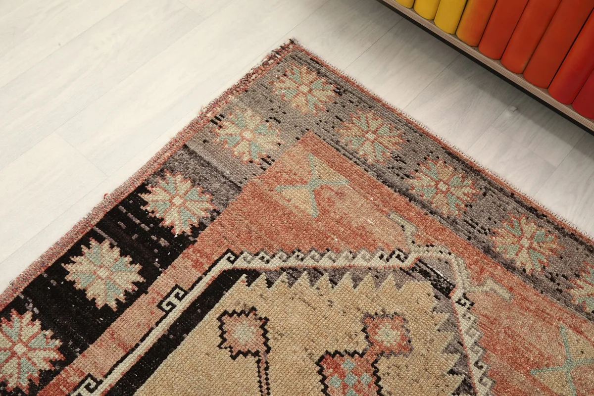 Corner detail of the rug, highlighting the gray border with floral designs and rust field