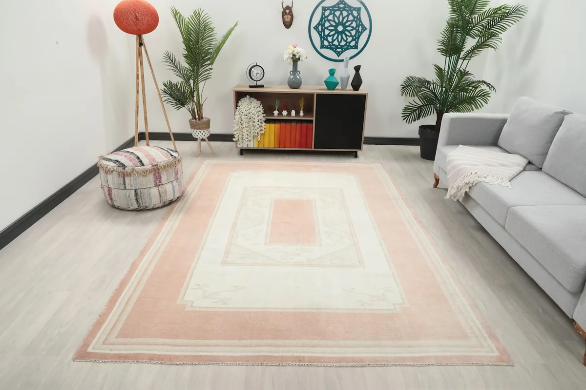 Vintage pink and ivory rug placed in a modern living room setting with a gray sofa