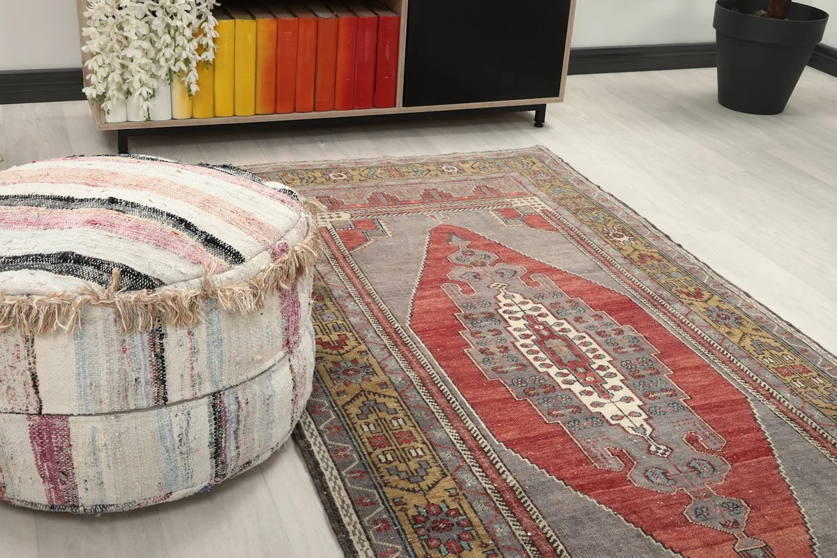 Close-up angle view of the rug's texture and colors next to a striped pouf
