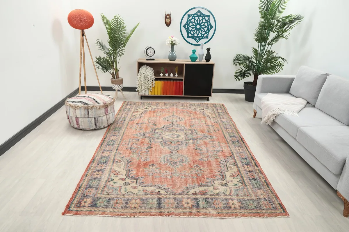 Vintage rust rug displayed in a bright living room setting with a gray sofa