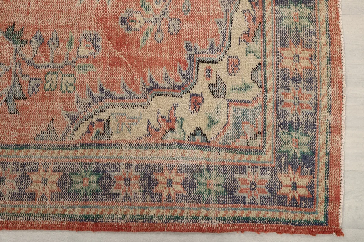 Detail of the rug's corner, highlighting the navy border and beige floral motifs