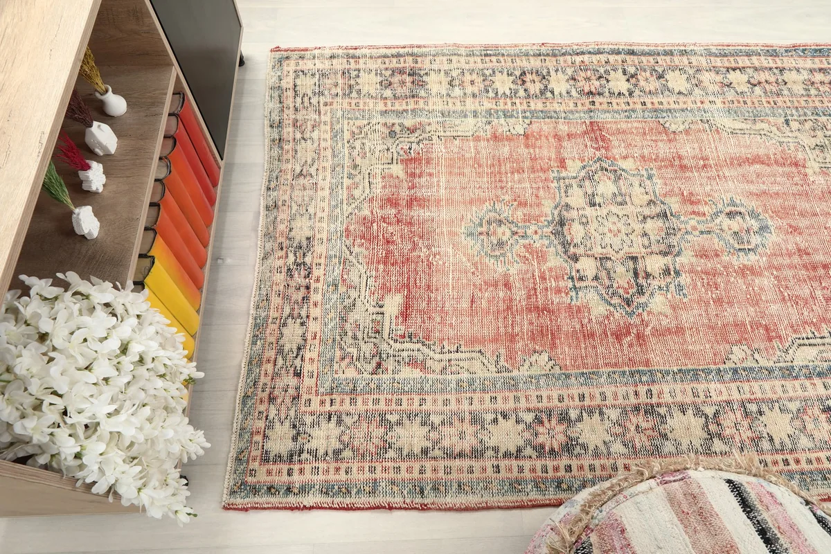 Wide shot of the vintage rug in a room, emphasizing its small size and decorative impact
