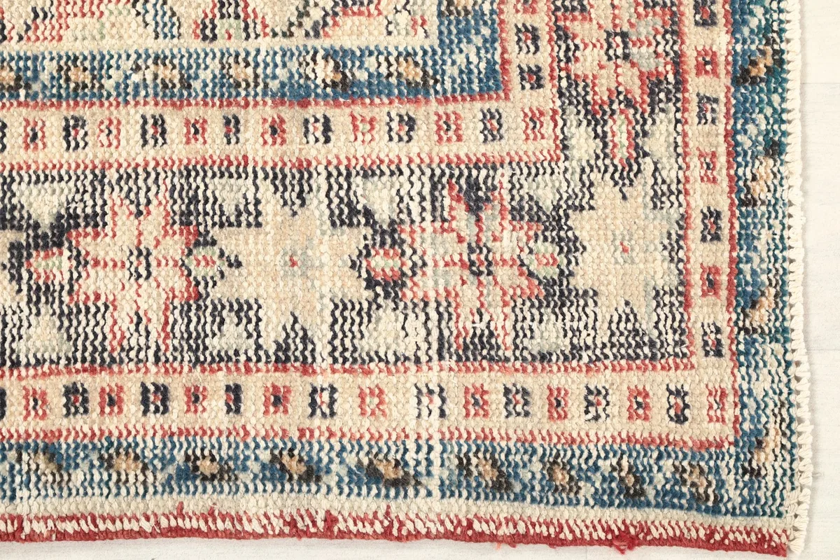 Detailed view of the rug's beige and blue geometric border design