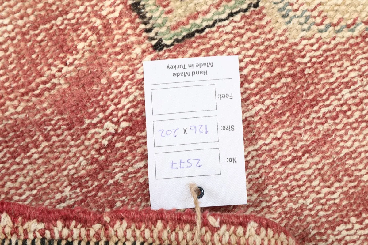 Close-up of the rug's back, displaying the hand-knotted cotton foundation and a size tag
