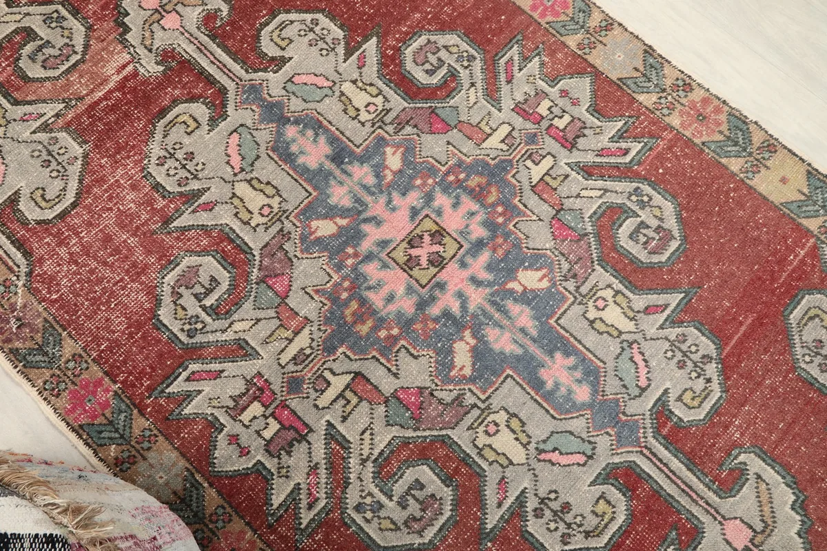 Overhead close-up of the rug's central gray and blue medallion with pink and yellow accents