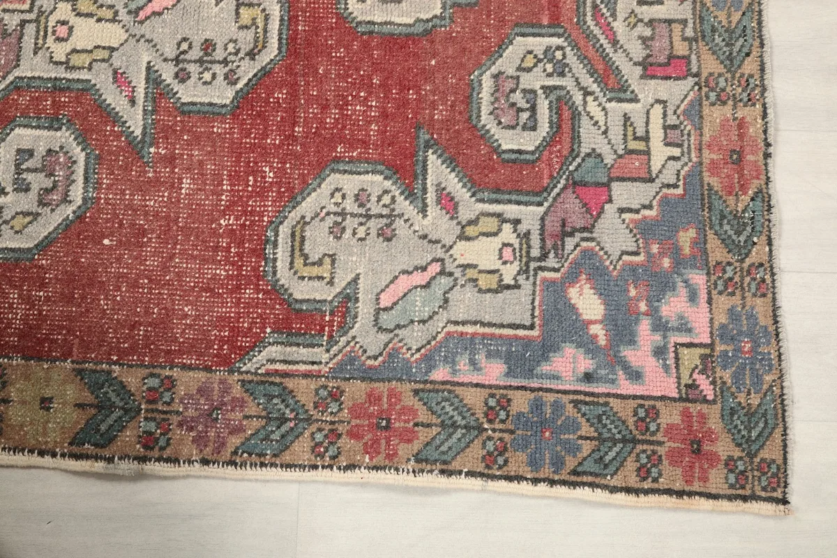 Detailed view of the rug's border design featuring floral and geometric motifs in beige, blue, and pink
