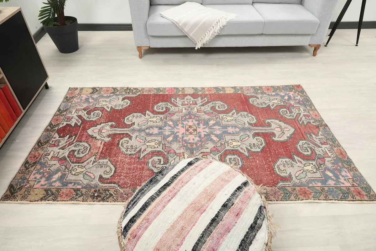 Overhead view of the rug in a room, with an ottoman in the foreground, showcasing its full design