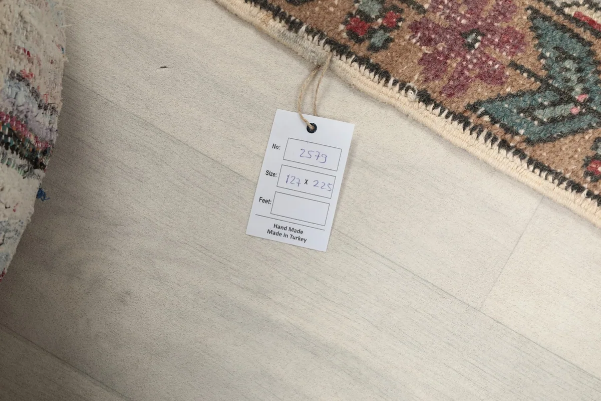 Product tag attached to the rug, indicating its handmade origin and size