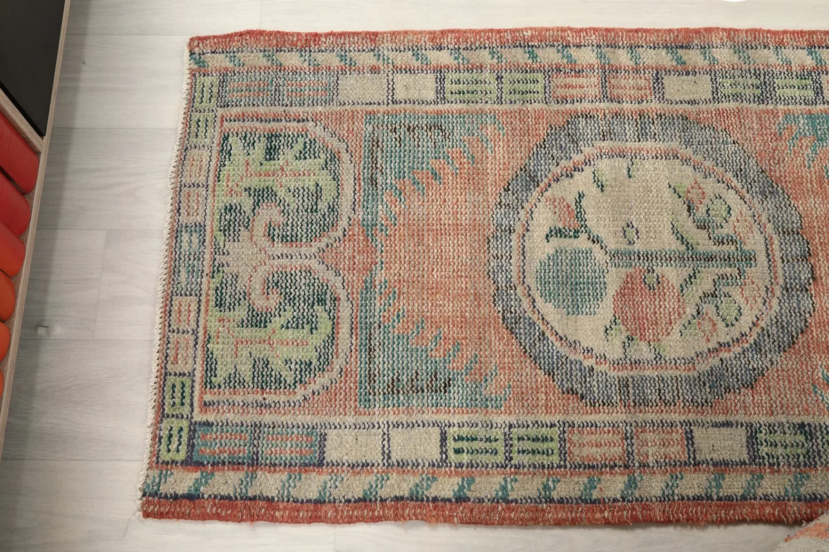 Angled shot of the rug's top half, focusing on the left side and its faded color variations.
