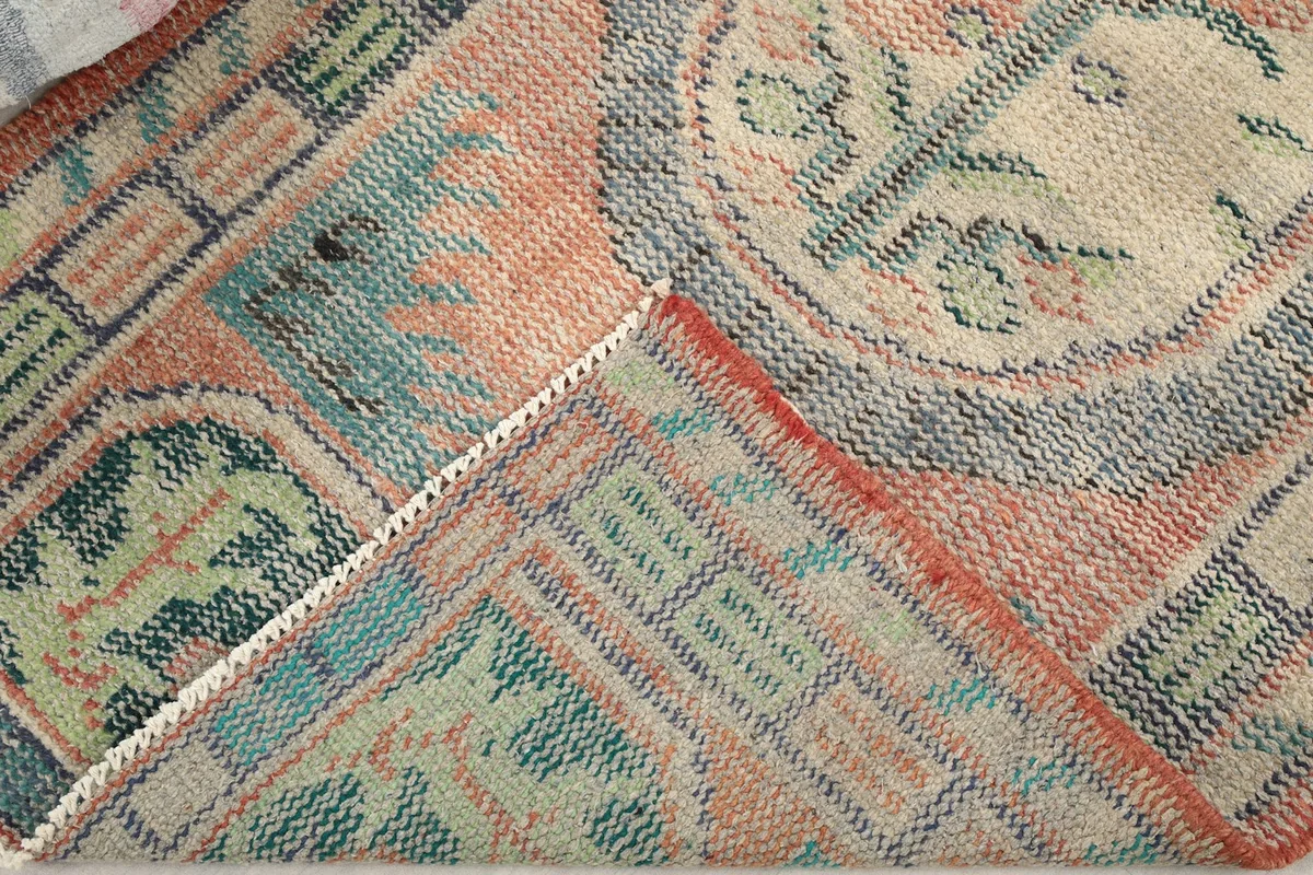 Folded corner of the rug revealing the cotton foundation and hand-knotted construction from the back.