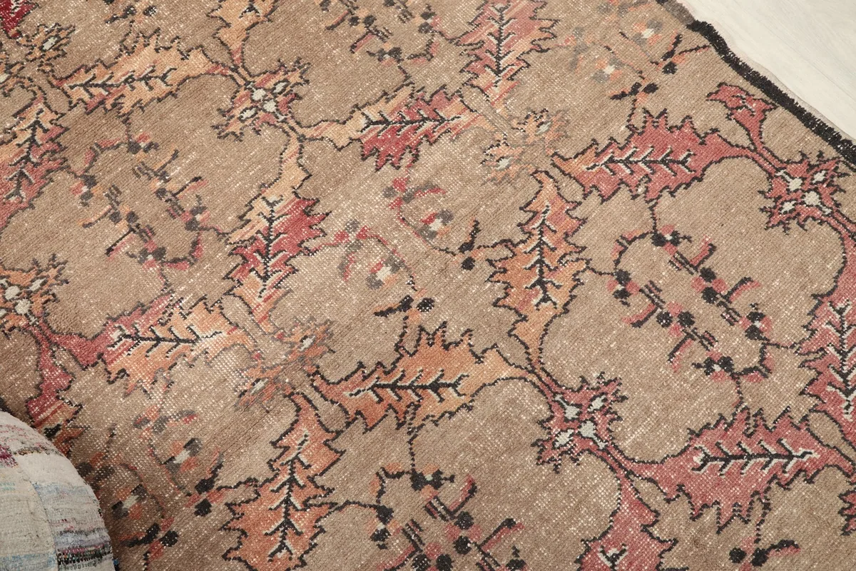 Detailed view of the rose and orange geometric motifs on the tan field