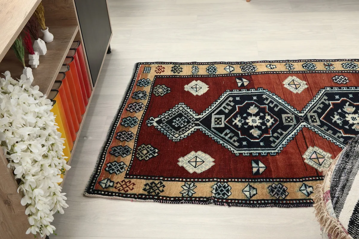 Wide angled view of the rug on the floor, showing its full length and patterns from a side perspective.
