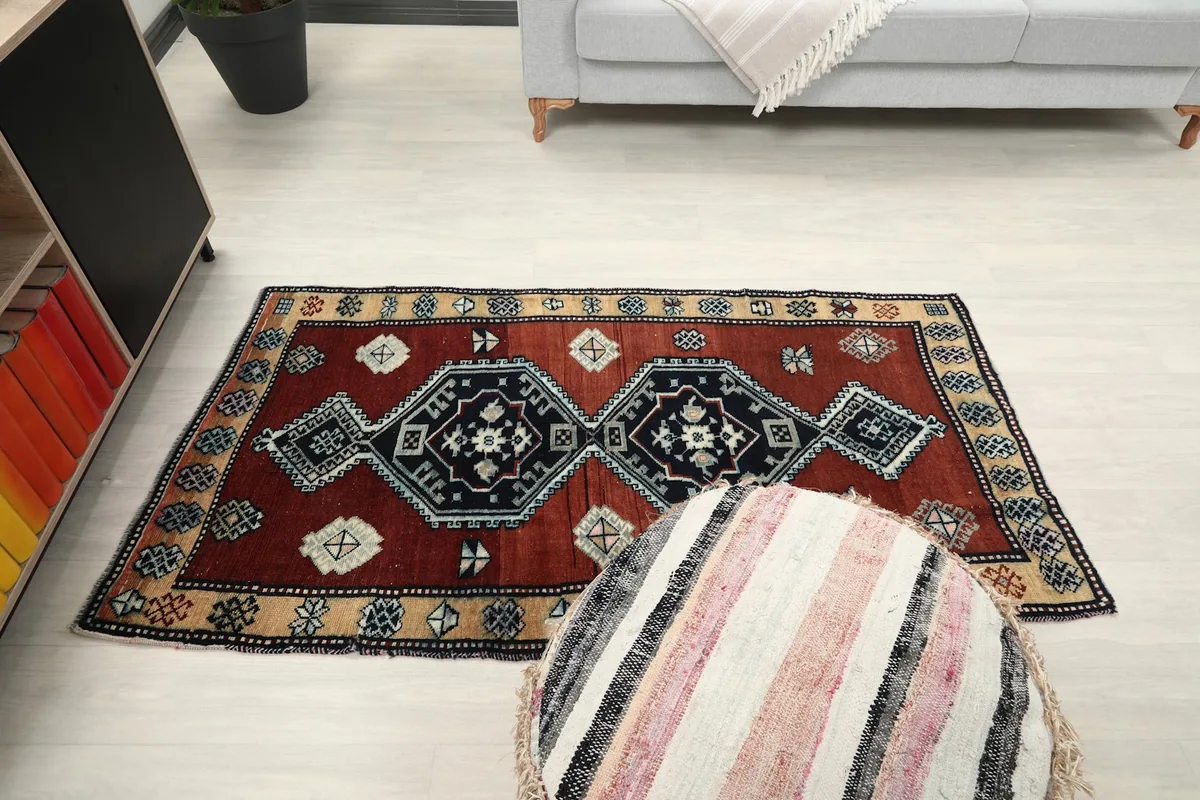 Overhead shot of the rust and navy rug in a living space, with a striped pouf in the foreground.