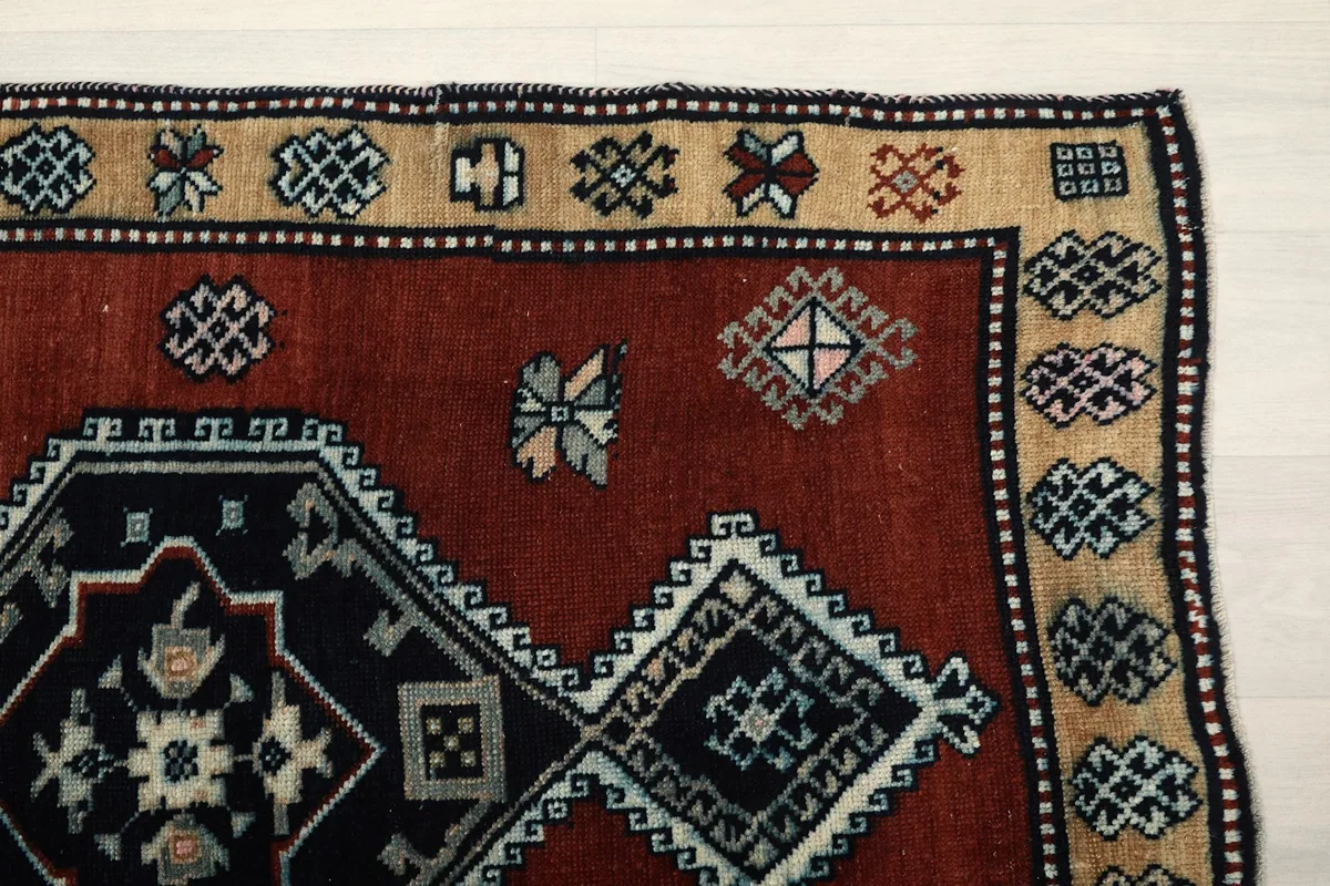 Detailed corner view of the rug, showing the rust field, tan border, and intricate geometric motifs.