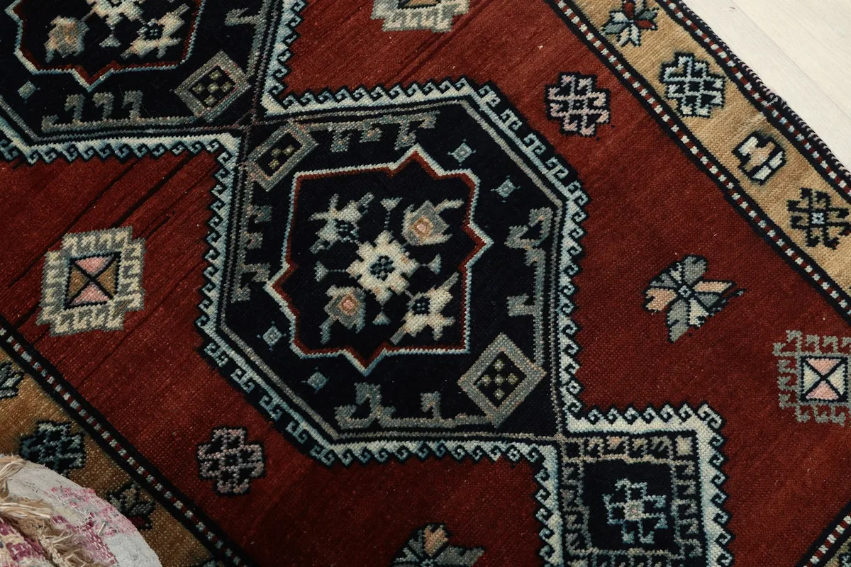 Close-up of the central navy medallion with ivory and gray details against the rust field.