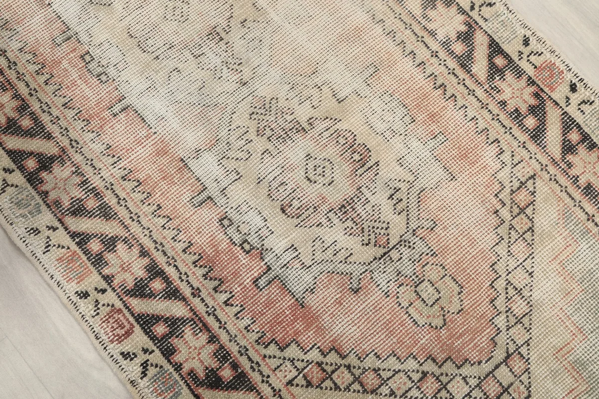 Close-up of the central geometric medallion and field variation in beige and rose
