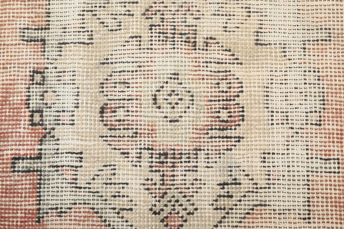 Texture close-up of the low wool pile and hand-knotted weave, showing faded color