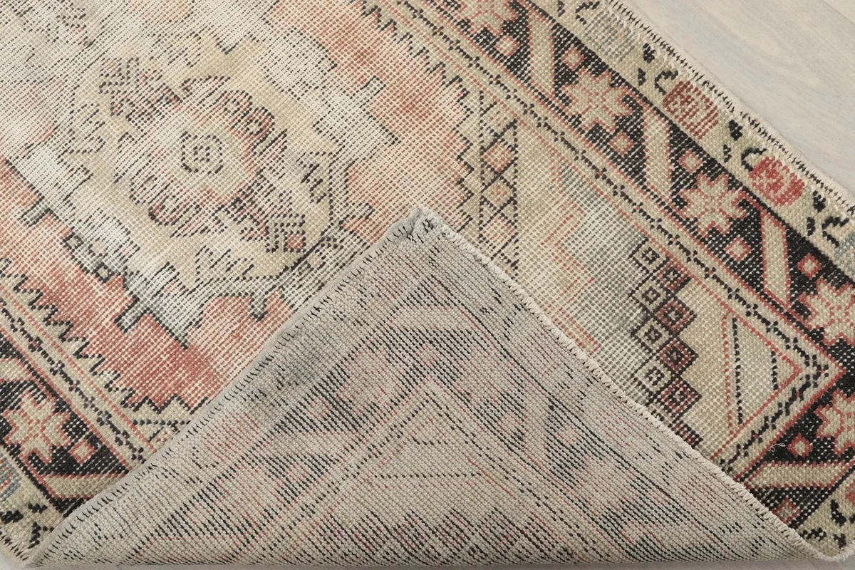 Corner of the rug folded back to show the cotton foundation and knotting