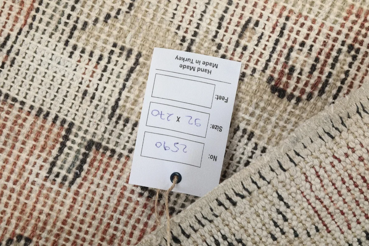 Tag on the back of the rug indicating its hand-made origin and size in cm