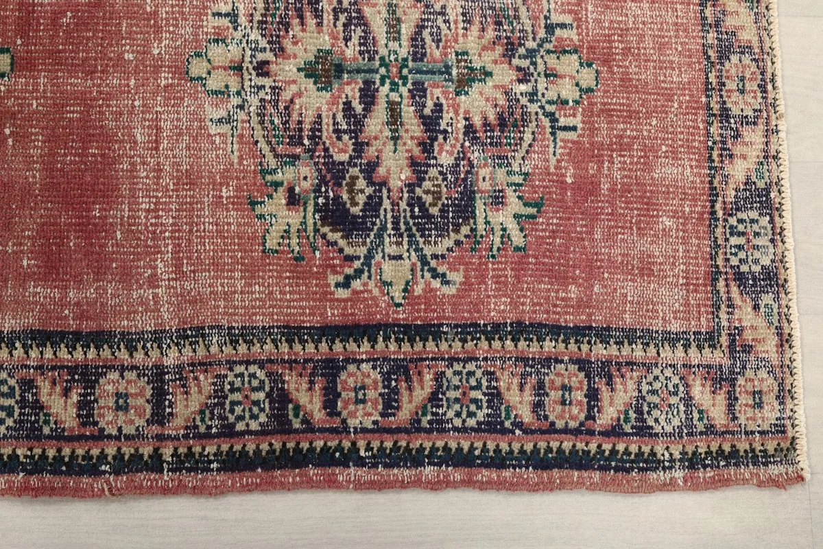 Detailed view of one end of the rose runner rug, highlighting the navy border and geometric patterns.
