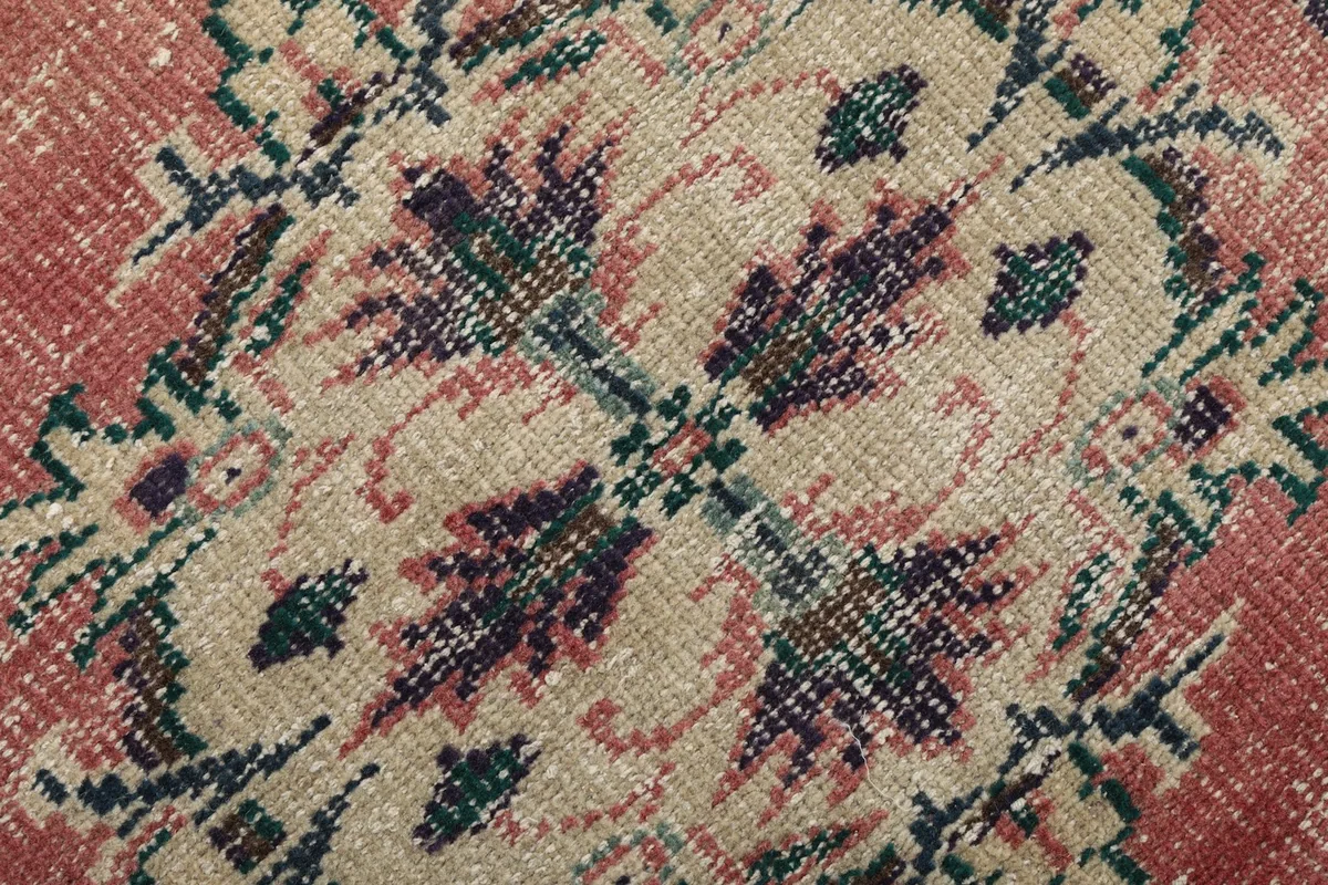 Extreme close-up showing the low wool pile and intricate knotting of the rose, navy, and beige pattern.