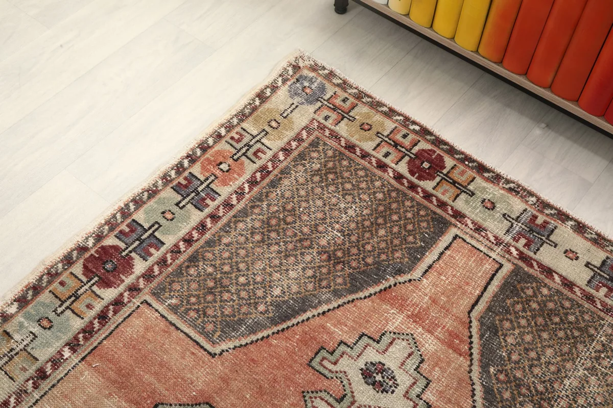 Close-up of the rug's top corner and border design, next to a colorful bookshelf