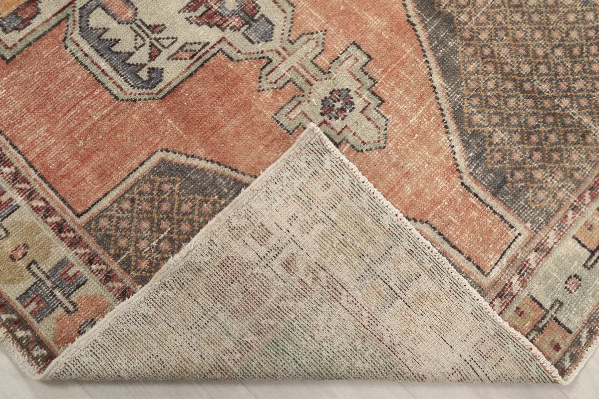 Corner of the rug folded back to reveal the cotton foundation and hand-knotted construction