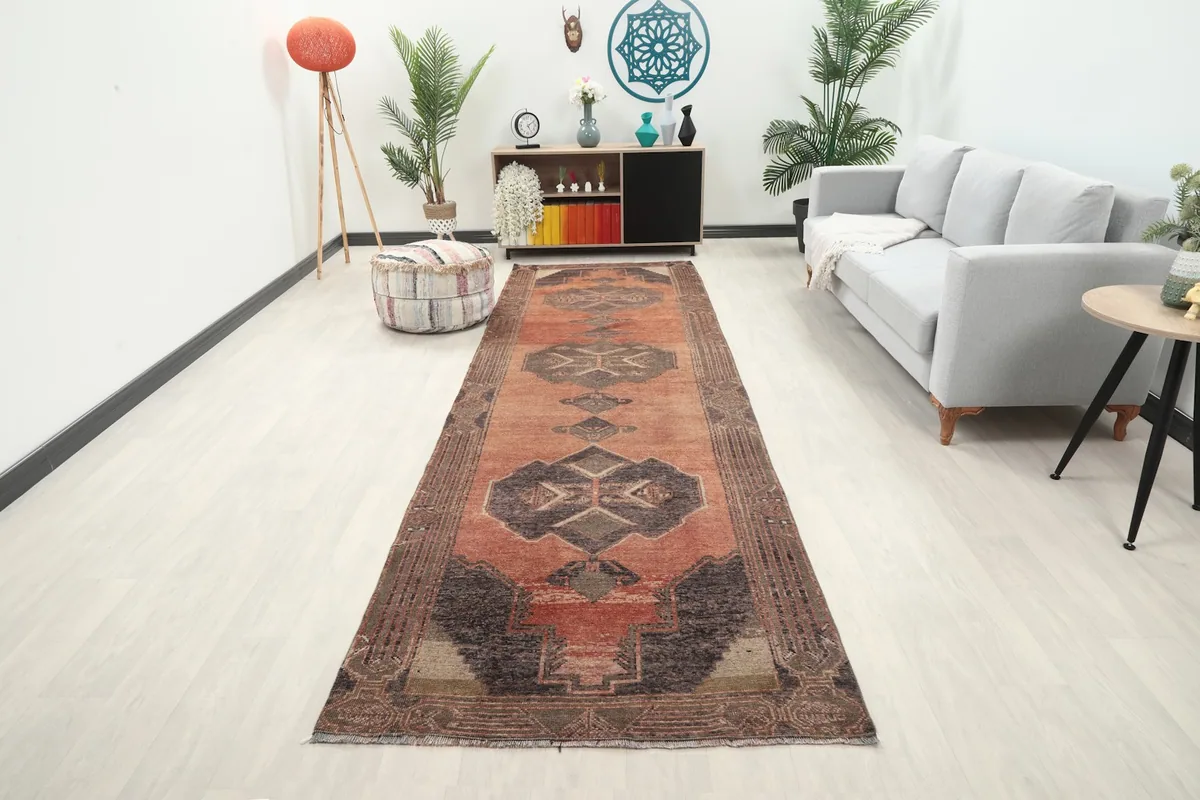 Rust runner rug in a modern living room setting with a gray sofa and plants