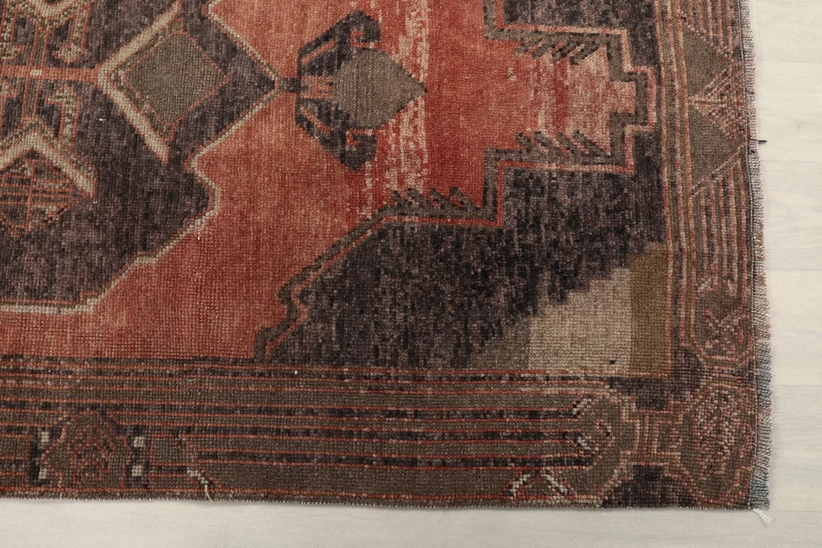 Detailed view of the rust and brown geometric patterns and border of the runner rug