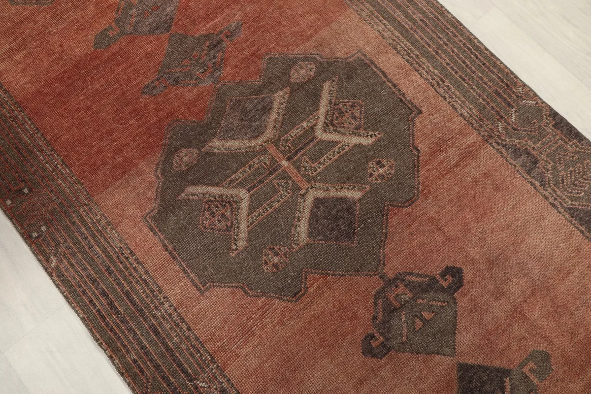 Close-up of a central tribal geometric motif in brown and beige on the rust runner